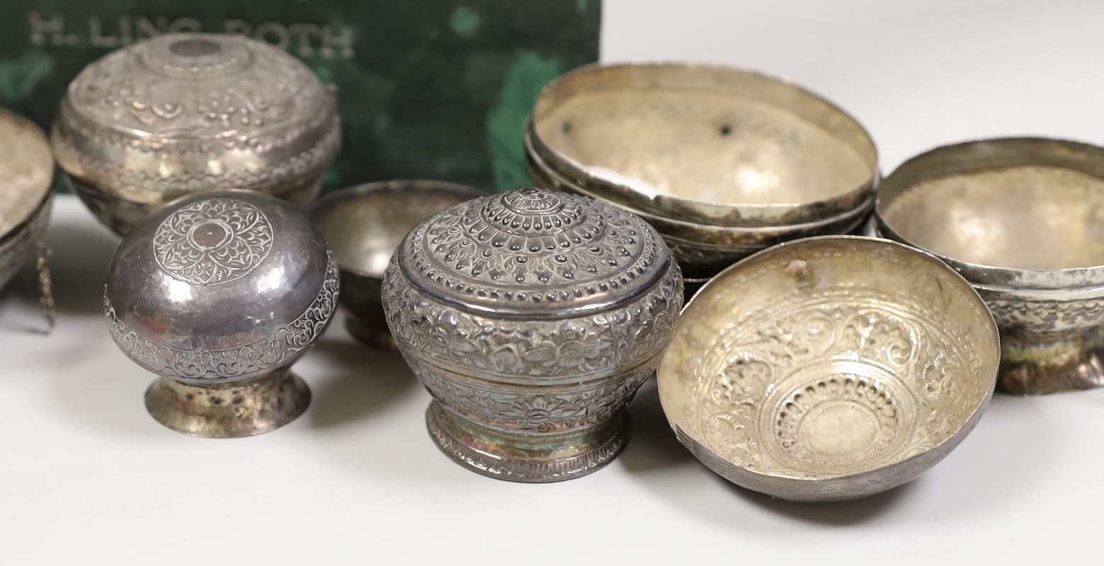 A collection of Malay Straits white metal circular betel nut boxes ('Chimbul'), comprising seven boxes and covers of various sizes (some damaged or missing chain fastenings) and two boxes lacking covers, gross weight 881